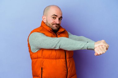 Mor arka planda izole edilmiş genç, beyaz kel bir adam. Kollarını uzatıyor, rahat bir konumda..