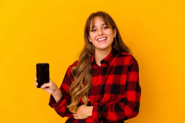 Junge Kaukasische Frau Hält Handy Isoliert Auf Gelbem Hintergrund Lacht — Stockfoto