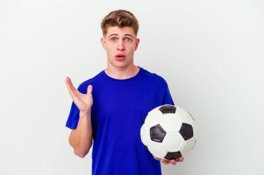 Arka planda izole bir şekilde futbol oynayan genç beyaz adam şaşırdı ve şok oldu..