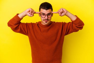 Sarı arka planda izole genç beyaz adam bir göreve odaklanmış, işaret parmaklarını işaret ediyor.