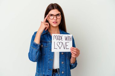 Beyaz arka planda izole edilmiş, boş bir alanda bir şey gösteren, gülümseyen ve işaret eden, aşk tabelasından yapılmış beyaz bir kadın..