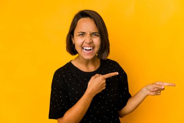 Sarı üzerine izole edilmiş genç İspanyol kadın işaret parmağıyla işaret ederek heyecanlanıyor..