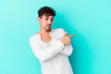 Mavi arka plan noktalarında izole genç beyaz adam, iki seçenek arasında seçim yapmaya çalışıyor.