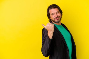 Orta yaşlı beyaz bir adam sarı arka plan noktalarında izole edilmiş, başparmak uzakta, gülüyor ve kaygısız..