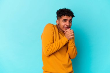 Genç Afro-Amerikalı kıvırcık adam mavi üzerine izole edilmiş korkmuş ve korkmuş.