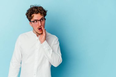 Kafkasyalı genç bir iş adamı mavi arka planda izole edilmiş bir şekilde gizli bir sıcak fren haberi veriyor.