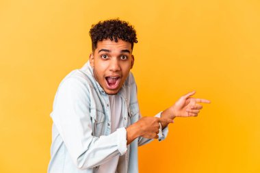 Genç Afro-Amerikan kıvırcık adamı, mor renkte izole edilmiş, işaret parmağıyla işaret ediyor..