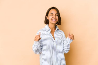 Genç İspanyol kadın kendini soyutlamış, iki parmağını da kaldırmış, gülümsüyor ve kendinden emin..