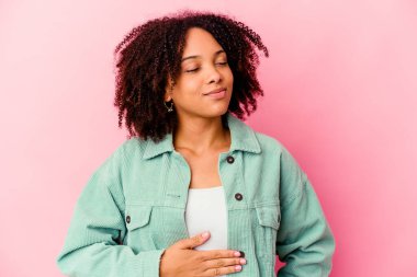 Genç Afro-Amerikan melez kadın karnına dokunuyor, nazikçe gülümsüyor, yemek yiyor ve tatmin oluyor..