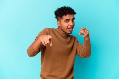 Genç Afro-Amerikalı kıvırcık adam mavi üzerine izole edilmiş, parmaklarıyla önden işaret ediyor..