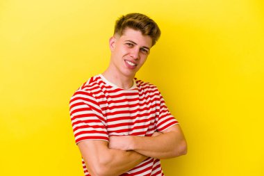 Sarı arka planda izole genç beyaz adam gülüyor ve eğleniyor..