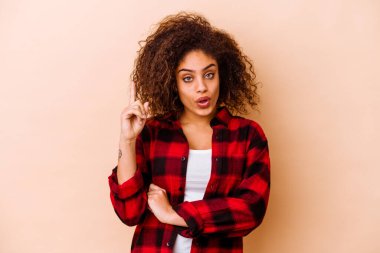 Genç Afrikalı Amerikalı kadın bej arka planda izole edilmiş. Harika bir fikri var, yaratıcılık kavramı..