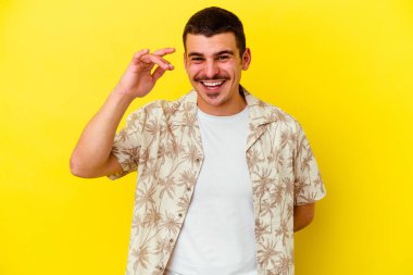 Sarı arka planda izole edilmiş genç, beyaz bir adam bir şeye gülüyor, ağızlarını elleriyle kapatıyor..
