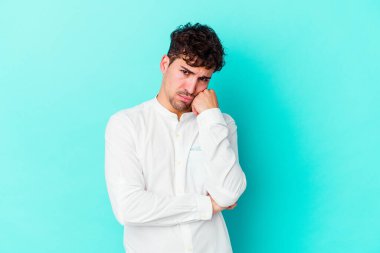 Mavi arka planda izole edilmiş genç beyaz adam tekrarlanan bir görevden yoruldu..