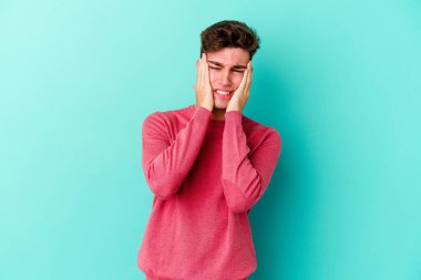 Kafkasyalı genç adam mavi arka planda izole edilmiş sızlanıyor ve ağlıyordu..