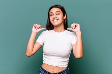 Mavi arka planda izole edilmiş genç Hintli kadın gururlu ve kendinden emin hissediyor, örnek olarak..