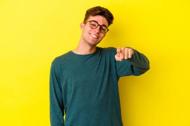 Sarı arka planda izole edilmiş genç beyaz adam öne bakan neşeli gülücükler.