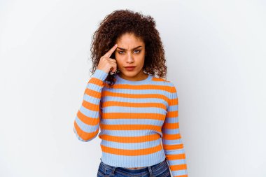Beyaz arka planda izole edilmiş genç bir Afrikalı Amerikalı kadın şakağı parmağıyla işaret ediyor, düşünüyor ve bir göreve odaklanıyor..