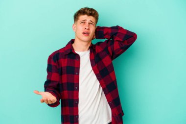 Mavi arka planda izole edilmiş genç beyaz adam öfkeyle bağırıyor..