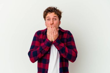 Beyaz arka planda izole edilmiş genç beyaz adam elleriyle ağzını kapatırken şok oldu..