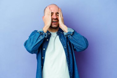 Mor arka planda soyutlanmış beyaz kel bir adam ellerini başının üstünde tutarak neşe içinde gülüyor. Mutluluk kavramı.