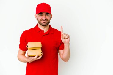 Beyaz arka planda izole edilmiş beyaz tenli teslimatçı bir numarayı parmağıyla gösteriyor..