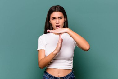 Mavi arka planda izole edilmiş genç Hintli kadın bir mola hareketi gösteriyor..