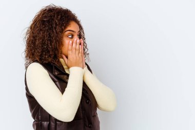 Genç Afrikalı Amerikalı bir kadın beyaz arka planda izole edilmiş. Düşünceli bir şekilde bir fotokopi odasına bakıyor. Ağzını eliyle kapatıyor..