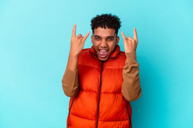 Genç Afro-Amerikan kıvırcık adamı mavi üzerine izole edilmiş boynuzlarını bir devrim konsepti olarak gösteriyor..