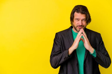 Kafkasyalı orta yaşlı bir adam sarı arka planda izole edilmiş bir plan yapıyor, bir fikir kuruyor..