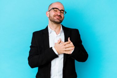 Mavi arka planda soyutlanmış beyaz saçlı genç bir adam dost bir ifadeye sahip, avuçlarını göğsüne bastırıyor. Aşk konsepti.