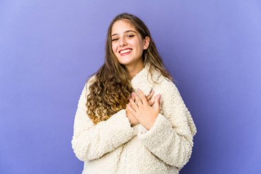 Genç, beyaz, sevimli bir kadın gülüyor. Elini yüreğine koyuyor. Mutluluk kavramı..