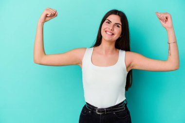 Genç beyaz kadın mavi arka planda izole edilmiş zafer sonrası yumruğunu kaldırıyor, kazanan konsept..
