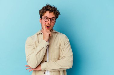 Mavi arka planda izole edilmiş gözlüklü genç bir beyaz adamın harika bir fikri var, yaratıcılık kavramı..