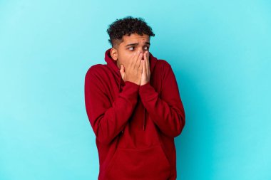 Genç Afro-Amerikalı kıvırcık adam mavi düşünceli bir şekilde izole edilmiş. Ağzını eliyle kapatan bir fotokopi odasına bakıyor..