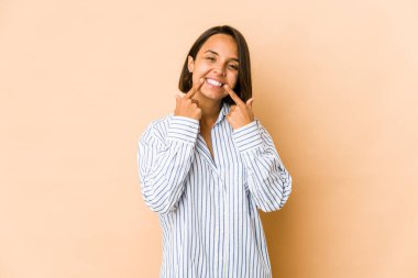 Genç İspanyol kadın yalnız gülümsüyor, parmaklarını ağzına doğrultuyor..