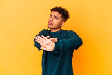 Genç Afro-Amerikalı kıvırcık adam, mor üzerine izole edilmiş, elini uzatmış, dur işareti göstererek, seni engelliyor..