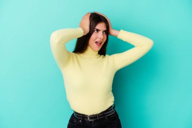 Mavi arka planda izole edilmiş genç beyaz kadın çığlık atıyor, çok heyecanlı, tutkulu, bir şeyden memnun..