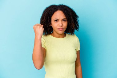 Genç Afro-Amerikan melez kadın izole edilmiş kameraya yumruk gösteriyor, agresif yüz ifadesi var..