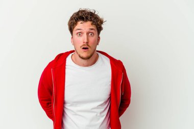 Beyaz arka planda izole edilmiş genç beyaz bir adam omuz silkiyor ve gözleri açık..