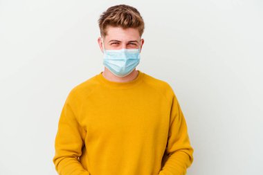 Koronavirüs maskesi takan genç bir adam beyaz arka planda izole edilmiş komik ve dostane bir dille konuşuyor..