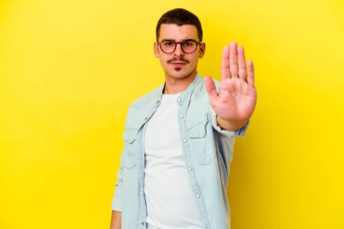 Sarı arka planda izole edilmiş genç, beyaz bir adam elini uzatmış, dur işareti gösteriyor ve seni engelliyor..