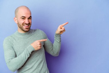 Mor arka planda izole edilmiş beyaz saçlı genç adam işaret parmağıyla işaret ederek heyecanlanıyor..