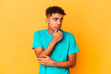 Genç Afro-Amerikalı kıvırcık adam, mor üzerine izole edilmiş, kafası karışmış, şüpheli ve güvensiz hissediyor..