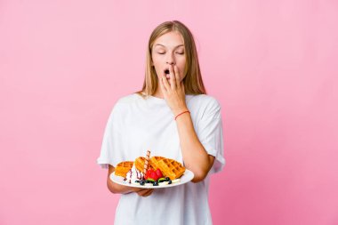 Genç Rus kadın waffle yerken kendini izole etmiş esniyordu. Ağzı eliyle kapatan yorgun bir jest yapıyordu..