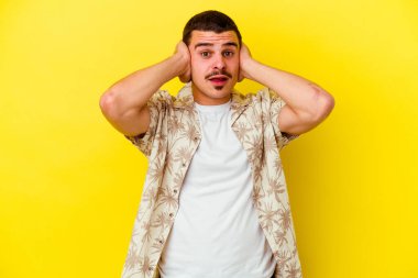 Kafkas asıllı genç adam sarı arka planda izole edilmiş kulakları kulaklarıyla kapatıyor çok fazla ses duymamaya çalışıyor..