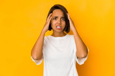 Sarı üzerine izole edilmiş genç İspanyol kadın mutlu bir şekilde ellerini başının üstünde tutuyor. Mutluluk kavramı.