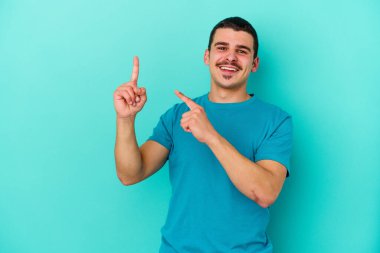 Genç beyaz adam mavi arka planda izole edilmiş dans ediyor ve eğleniyor..