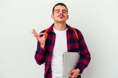 Beyaz arka planda dizüstü bilgisayar tutan beyaz tenli genç bir öğrenci yoğun çalışma gününden sonra dinleniyor. Yoga yapıyor..