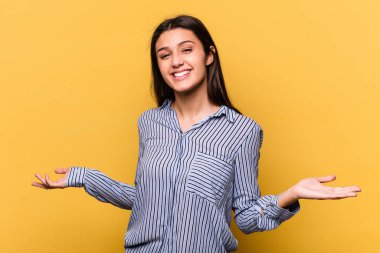 Sarı arka planda izole edilmiş genç Hintli kadın hoş bir yüz ifadesi sergiliyor..